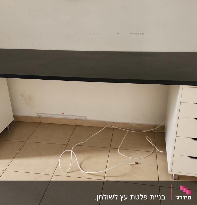 שולחן עבודה עם מגירות לבנות וכבל חשמל על הרצפה